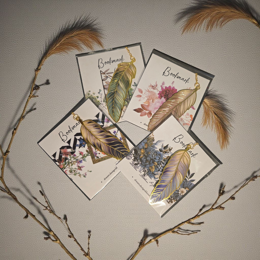 flatlay of gold feather planner bookmarks by dream.design.bloom featuring Whisper Dreams, Azure Blooms, Arbor Designs and Celestial Blooms colour palettes