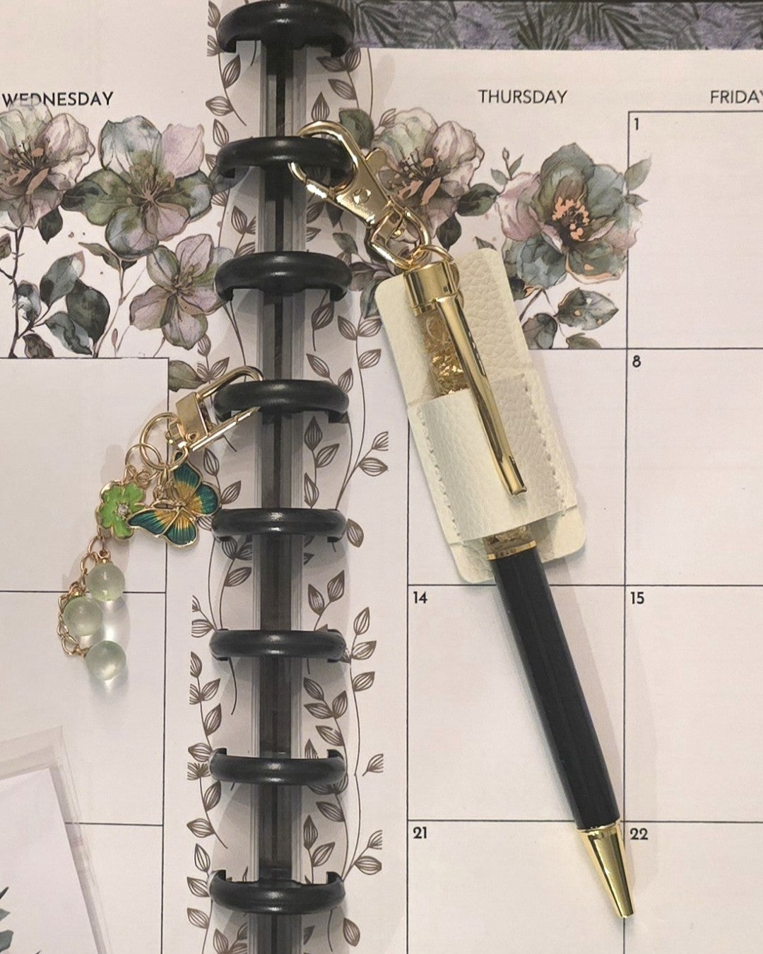 collection of dream.design.bloom discbound planner accessories including black discs, pen holders, and key charms designed to combine beauty, function, and creative organisation