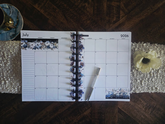 Discbound Monthly Planner in Azure Blooms colour palette for July 2026 on a wooden surface with decorative elements.