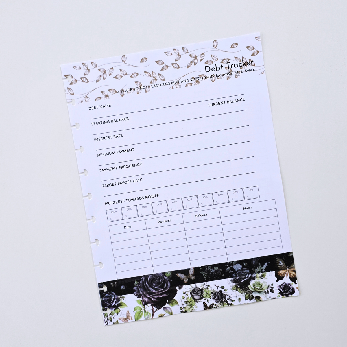 A discbound Debt Tracker planner page with black text fields, a white background, and floral rose illustrations in black, gray, and muted green along the top and bottom borders, photographed on a light neutral background. Disc Bound Planner. Discbound insert