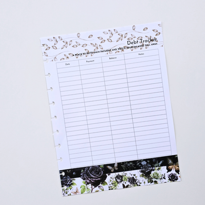 A discbound debt tracker notebook page with lined fields for date, percentage, balance, and notes, decorated with a floral vine border at the top and a black rose pattern at the bottom, shown on a light grey background. Disc Bound Planner