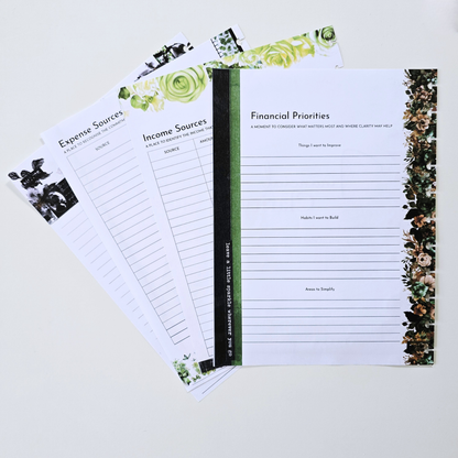 A set of printed financial planning insert notepads fanned out on a light neutral background. The notepads have white pages with black text and lines, decorated with green floral borders and a dark green spine. Disc Bound Planner. Discbound