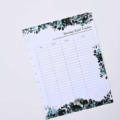 A discbound planner insert titled 'Savings Goal Tracker' with a white page, black grid lines, and teal and green floral illustrations along the top and bottom borders, photographed on a light gray background. Disc Bound Planner