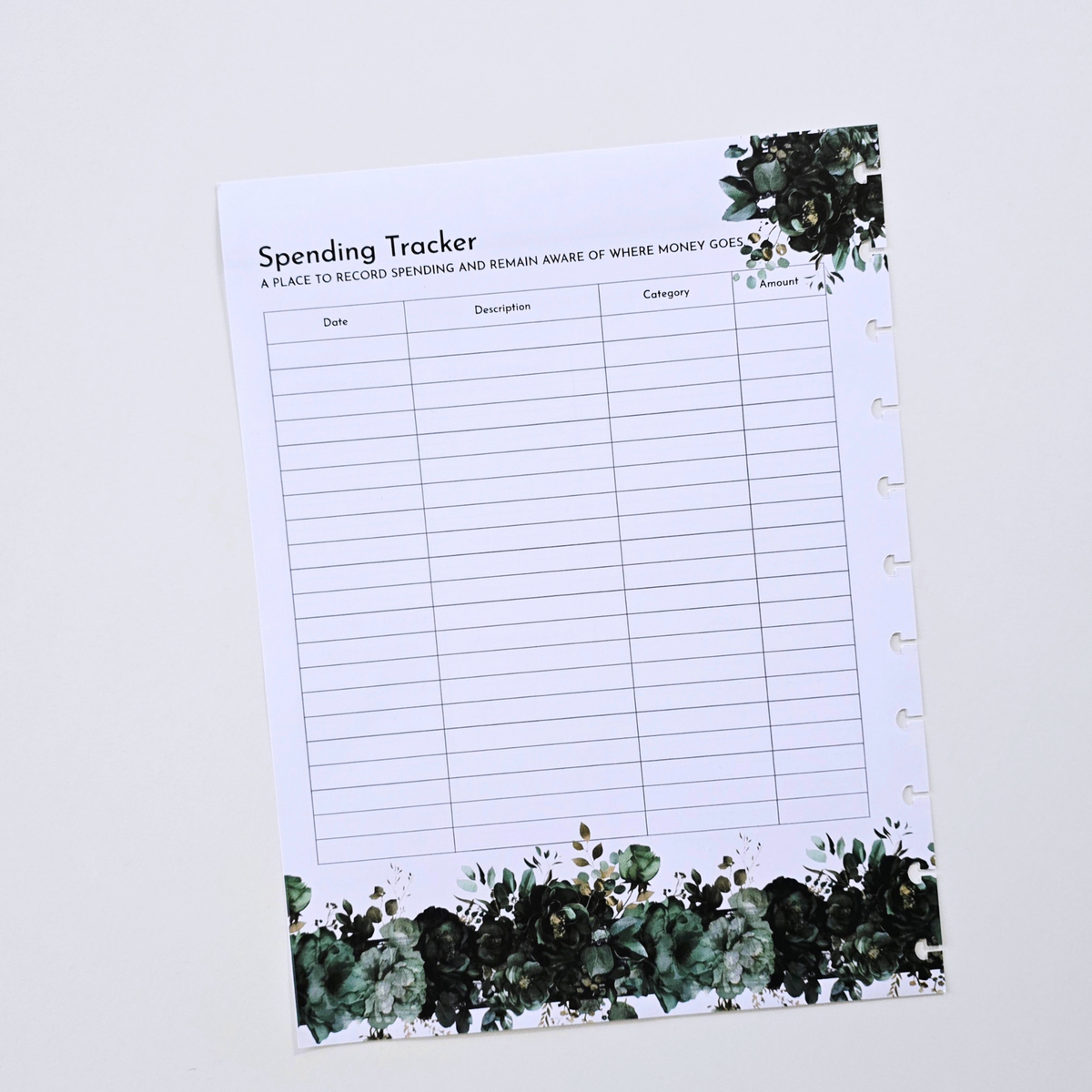 A white discbound spending tracker sheet with black text and green watercolor floral borders at the top and bottom, photographed on a light gray background. Disc Bound Planner. Discbound Insert