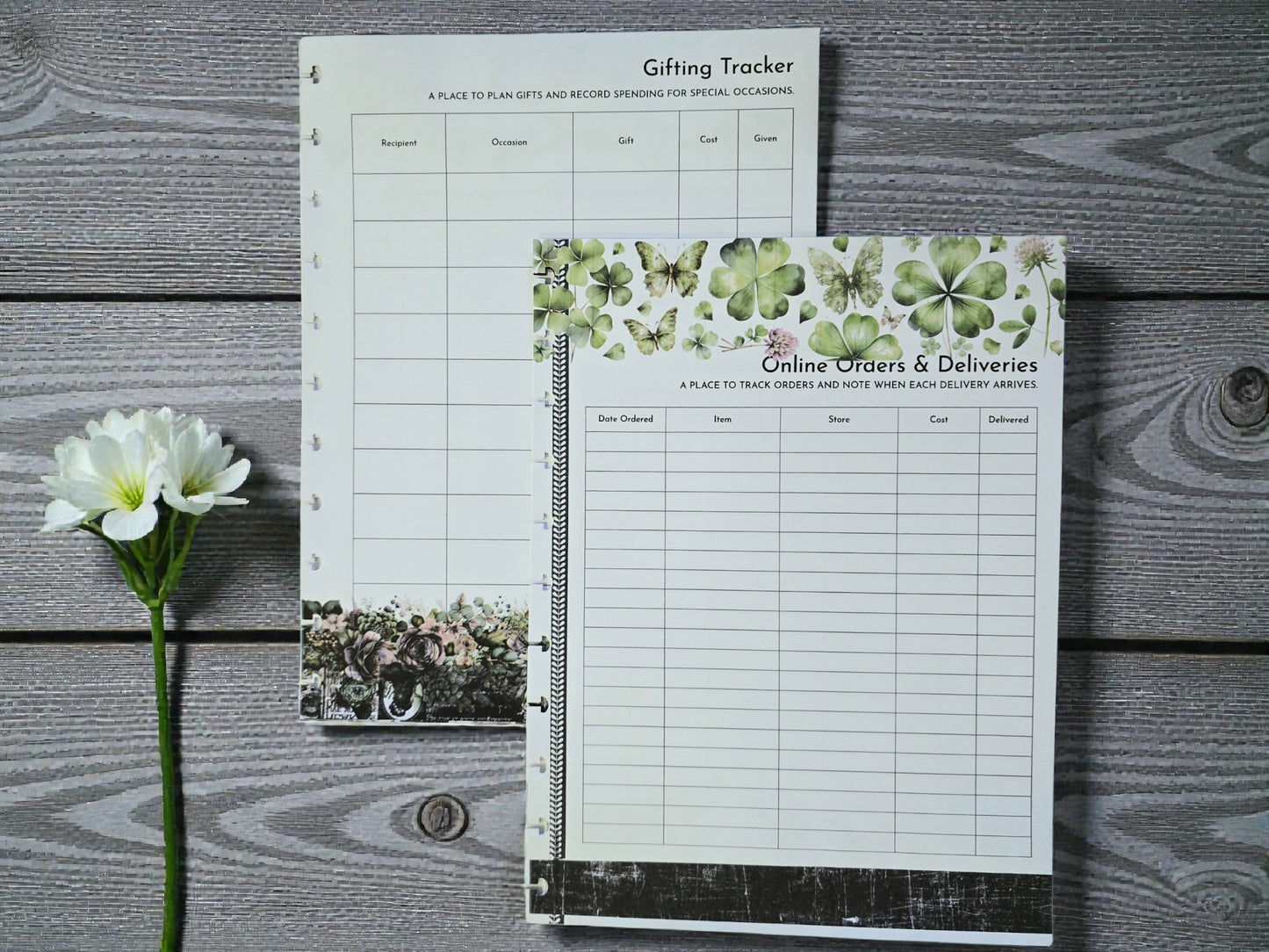 Two planner sheets on a wooden surface with a flower.