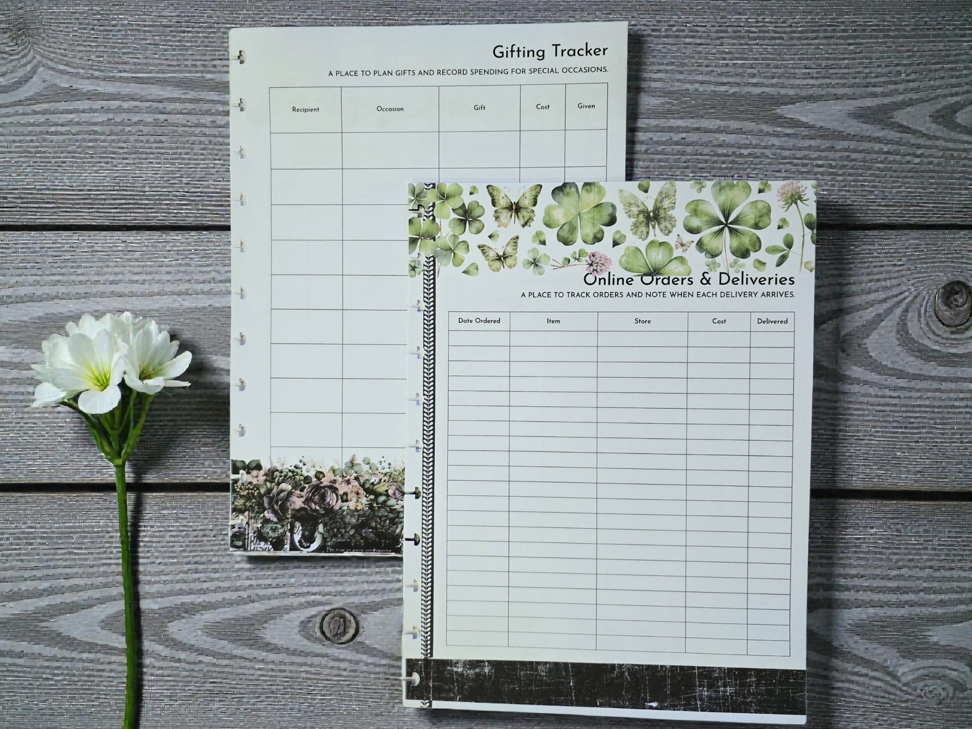 Two planner sheets on a wooden surface with a flower.