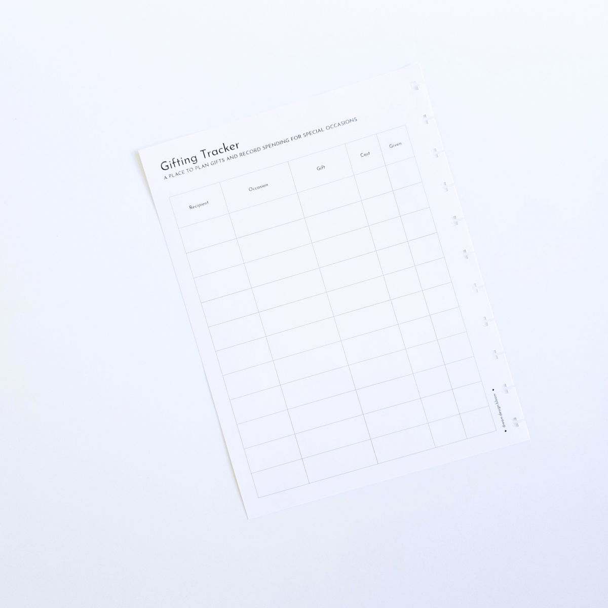 A white gift tracker discbound planner insert with a minimalist grid layout and black text, photographed at an angle on a clean white background. Disc Bound Planner. 