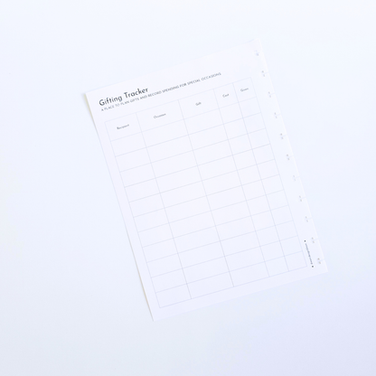 A white gift tracker discbound planner insert with a minimalist grid layout and black text, photographed at an angle on a clean white background. Disc Bound Planner. 